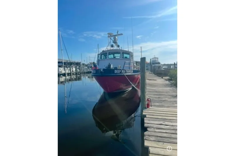 Deep Sea Traveler Yacht Photos Pics Red and black commercial boat docked at a marina, labeled "Deep Sea Traveler," under clear blue sky.