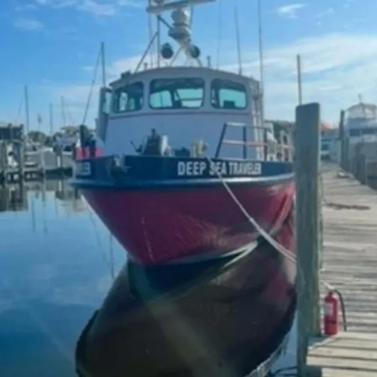 Deep Sea Traveler Yacht Photos Pics Red and black commercial boat docked at a marina, labeled "Deep Sea Traveler," under clear blue sky.