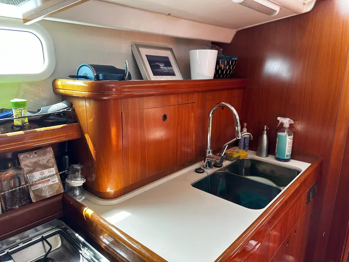 2.0 Impulsive Yacht Photos Pics 2005 Beneteau 57 yacht kitchen with wooden cabinetry and stainless steel sink.