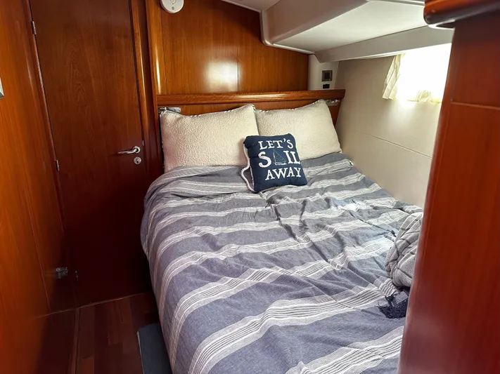 2.0 Impulsive Yacht Photos Pics Cozy cabin interior of 2005 Beneteau 57 yacht with striped bedding and nautical pillow.
