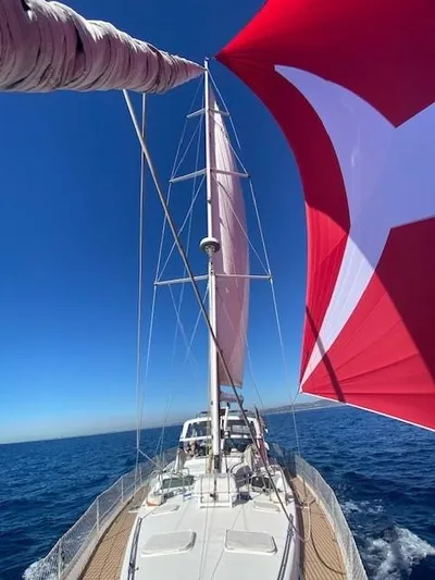 2.0 Impulsive Yacht Photos Pics Sailing on a 2005 Beneteau 57 yacht with vibrant red sails against a clear blue sky.