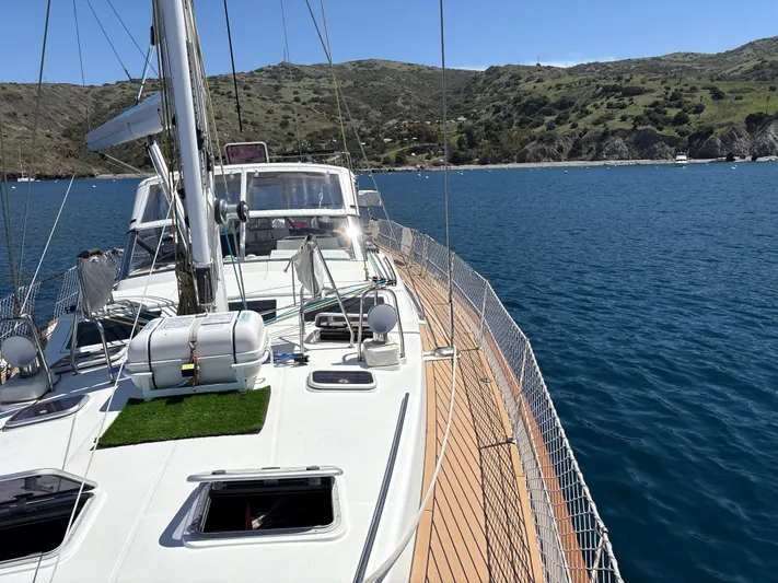 2.0 Impulsive Yacht Photos Pics Sailing yacht Beneteau 57, 2005 model, cruising on a serene blue sea near a hilly coastline.