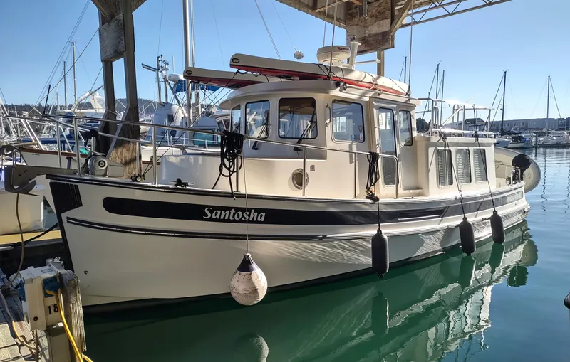 Santosha Yacht Photos Pics 2006 Nordic Tug 32 docked in a marina, featuring a classic design and sturdy build.
