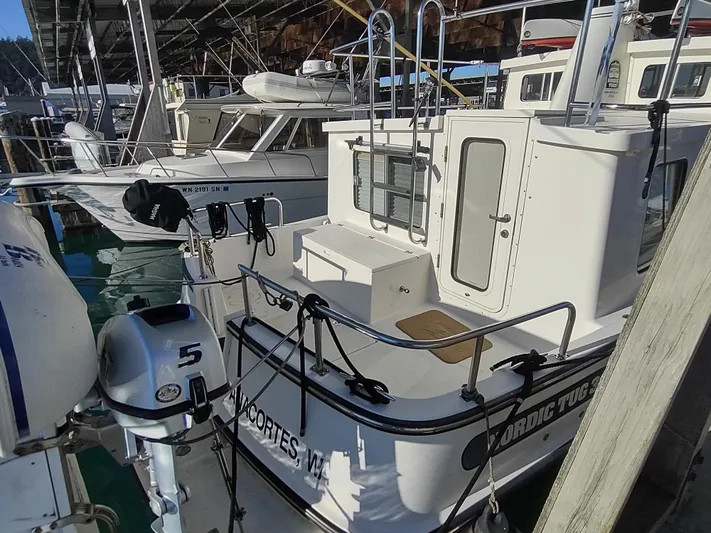 Santosha Yacht Photos Pics 2006 Nordic Tug 32 docked in a marina, featuring a white exterior and visible outboard motor.