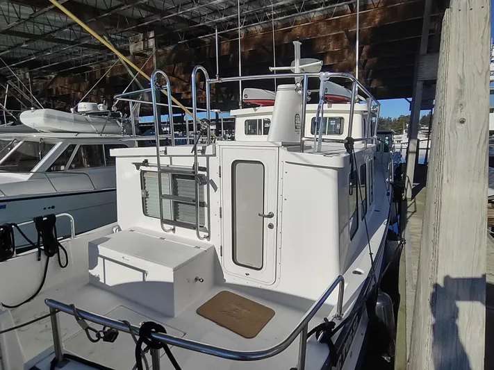 Santosha Yacht Photos Pics 2006 Nordic Tug 32 docked in a marina, showcasing its rear deck and cabin entrance.