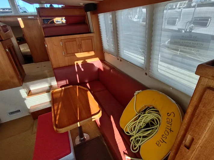 Santosha Yacht Photos Pics Interior of a 2006 Nordic Tug 32 with red seating and wooden table.