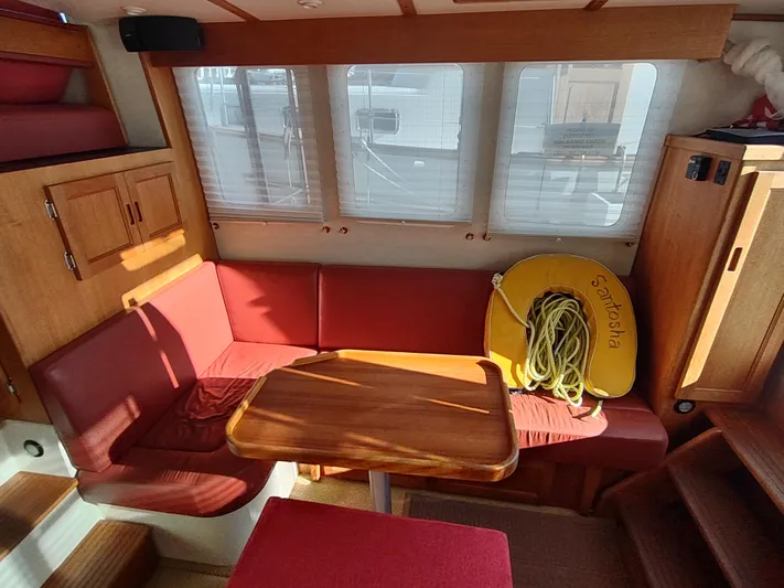 Santosha Yacht Photos Pics Interior of 2006 Nordic Tug 32 with red seating and wooden table.