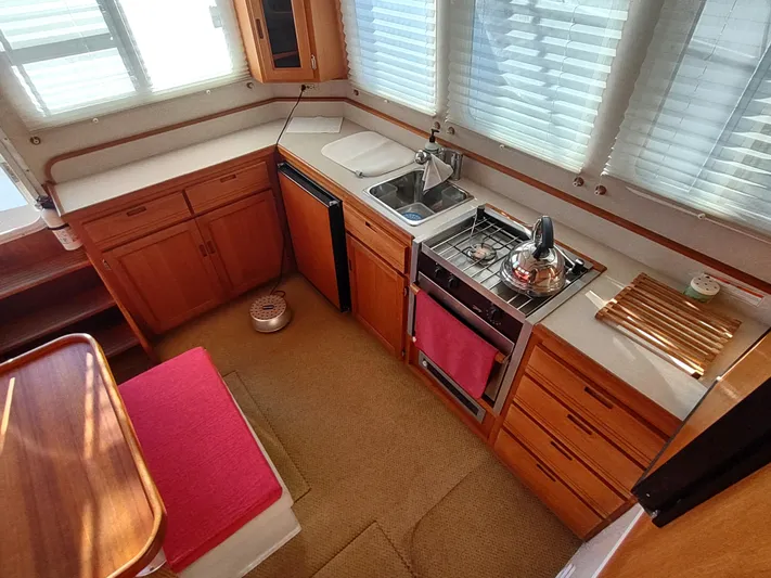 Santosha Yacht Photos Pics Interior of 2006 Nordic Tug 32 galley with wood cabinetry and compact kitchen appliances.