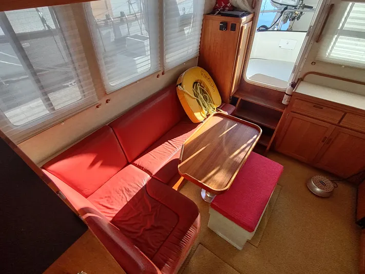 Santosha Yacht Photos Pics Interior of 2006 Nordic Tug 32 with red seating and wooden table.