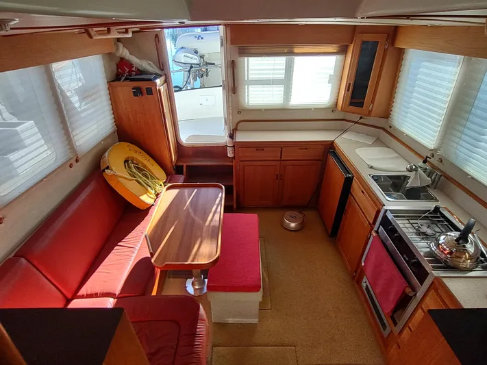 Santosha Yacht Photos Pics Interior of 2006 Nordic Tug 32 with red seating, kitchen, and dining area.