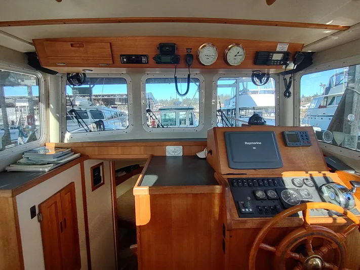 Santosha Yacht Photos Pics 2006 Nordic Tug 32 boat interior with navigation equipment and wooden steering wheel.