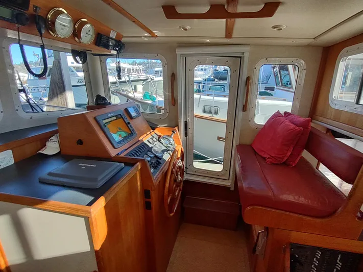 Santosha Yacht Photos Pics 2006 Nordic Tug 32 interior with helm, navigation equipment, and red seating.