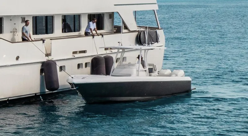  Yacht Photos Pics 2016 Intrepid 327 Center Console boat docked beside a larger yacht on calm water.