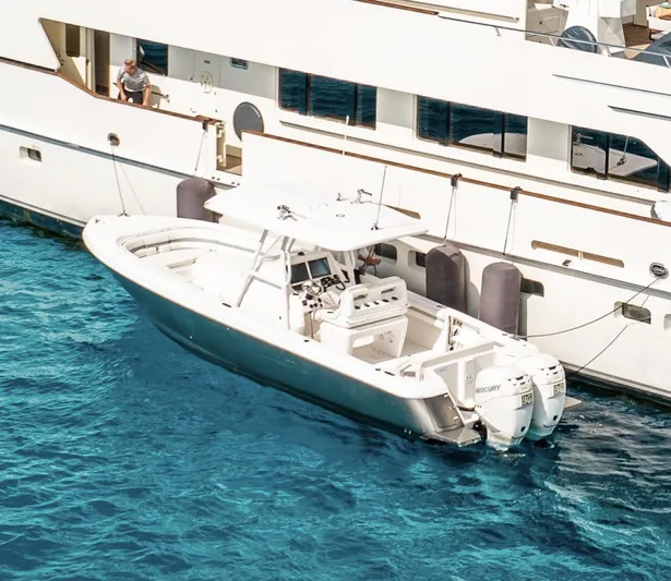  Yacht Photos Pics 2016 Intrepid 327 Center Console boat docked beside a larger yacht in clear blue water.