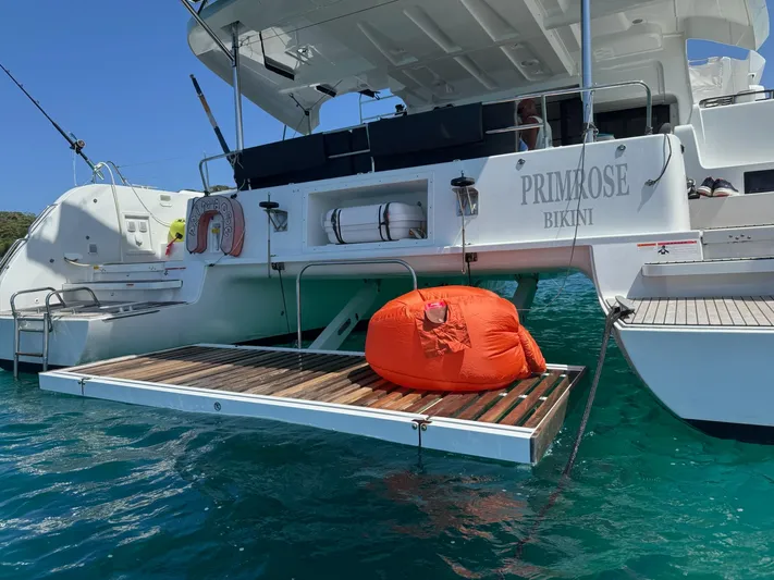 Primrose Yacht Photos Pics 2023 Lagoon 46 catamaran with orange bean bag on deck, floating in clear blue water.