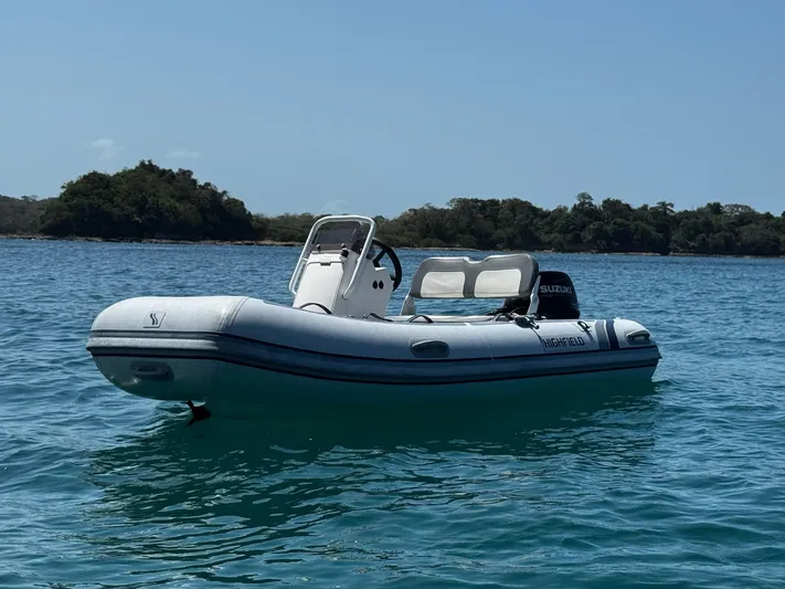 Primrose Yacht Photos Pics A small inflatable boat floating on calm blue water, with trees in the background.