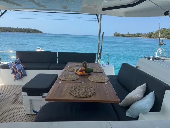 Primrose Yacht Photos Pics 2023 Lagoon 46 yacht deck with dining table, ocean view, and comfortable seating.