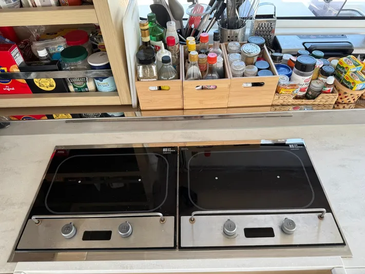 Primrose Yacht Photos Pics Modern kitchen setup on a 2023 Lagoon 46 yacht with dual stovetops and organized spices.