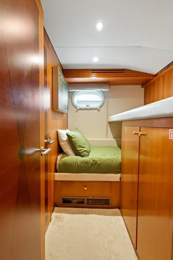 Magic Yacht Photos Pics Cozy cabin interior of 2005 Hatteras 100 Motor Yacht with wood paneling and green bedding.