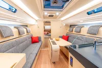 2023 Dehler 34 yacht interior with modern design, featuring gray seating, red cushions, and wooden accents.
