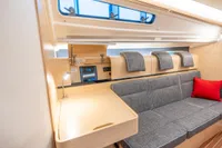 2023 Dehler 34 yacht interior with modern seating, wooden desk, and red cushion.