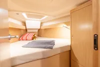 Cozy cabin interior of 2023 Dehler 34 yacht with bed, wooden cabinetry, and soft lighting.