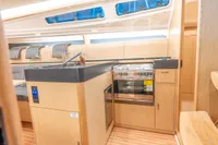 2023 Dehler 34 yacht interior with modern kitchen, featuring wood cabinetry and stainless steel appliances.