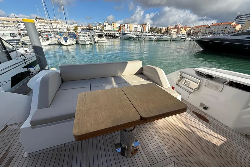  Yacht Photos Pics 2023 Ferretti Yachts 580, elegant deck seating with table, marina view.