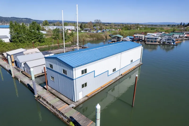  Yacht Photos Pics Aerial view of 1985 Custom Larson Boathouse on calm water, blue roof, surrounded by docks.