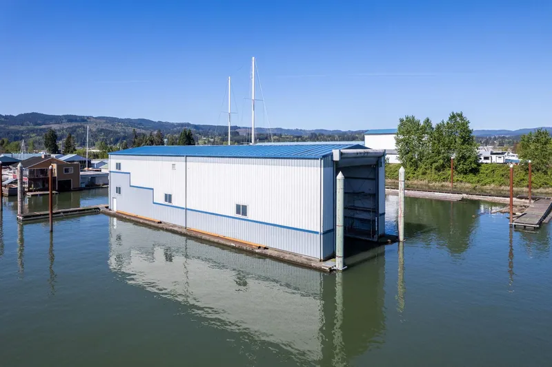  Yacht Photos Pics Floating boathouse on calm water, Custom Larson model, 1985, with blue roof and scenic backdrop.