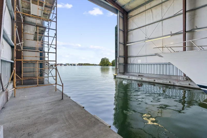  Yacht Photos Pics Boathouse interior with water view, scaffolding, and partial boat, Custom Larson Boathouse, 1985.