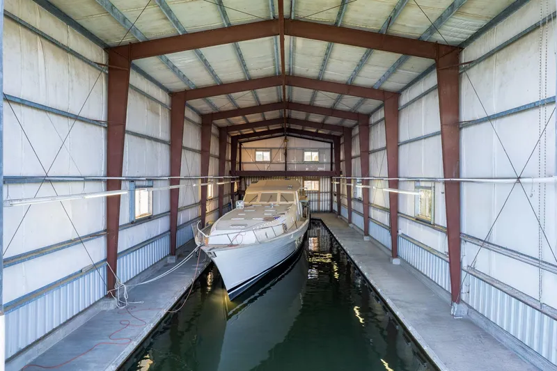  Yacht Photos Pics A 1985 Custom Larson Boathouse with a yacht docked inside, featuring metal beams and waterway.