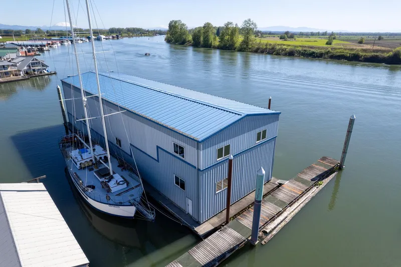  Yacht Photos Pics Aerial view of 1985 Custom Larson Boathouse with sailboat on a serene river.