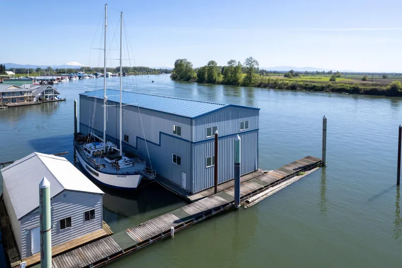  Yacht Photos Pics A 1985 Custom Larson Boathouse with sailboat on a serene river.
