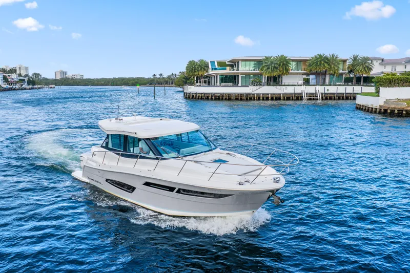  Yacht Photos Pics 2024 Regal 38 XO yacht cruising on a scenic waterway near luxury waterfront homes.