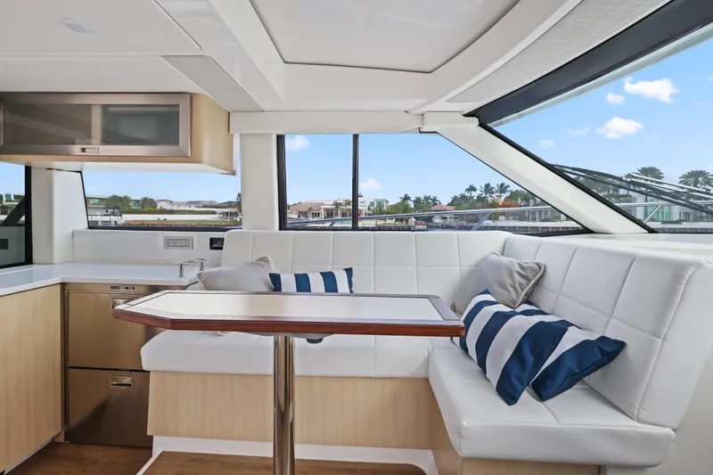  Yacht Photos Pics 2024 Regal 38 XO yacht interior with white seating, striped cushions, and a sleek dining table.