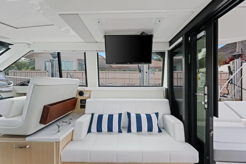  Yacht Photos Pics 2024 Regal 38 XO yacht interior with white seating, striped cushions, and mounted TV.