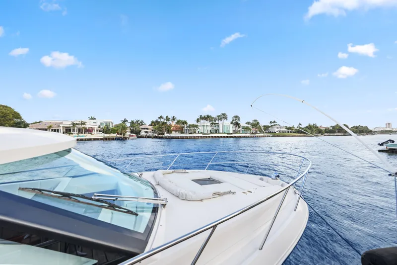  Yacht Photos Pics 2024 Regal 38 XO yacht cruising on a sunny day near waterfront homes.