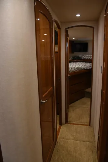 Crank It Up Yacht Photos Pics Interior hallway of a 2014 Viking 62 Convertible yacht with wooden doors and carpeted floor.