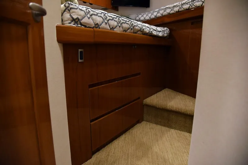 Crank It Up Yacht Photos Pics Interior cabin of a 2014 Viking 62 Convertible yacht with wooden drawers and a cushioned bed.