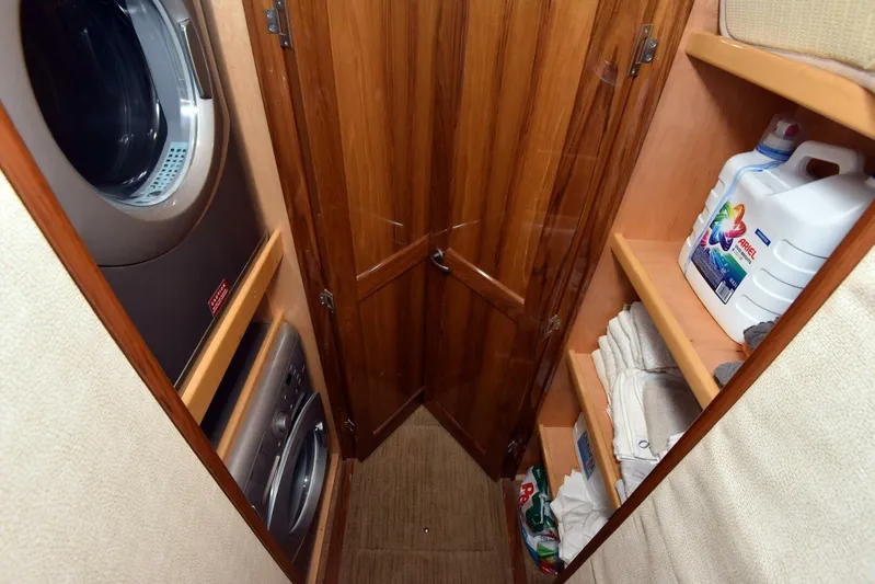 Crank It Up Yacht Photos Pics Laundry area on 2014 Viking 62 Convertible yacht with washer, dryer, and storage shelves.
