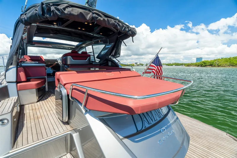 Damare Yacht Photos Pics 2022 Cranchi M 44 HT yacht with red seating, docked by a scenic waterfront.