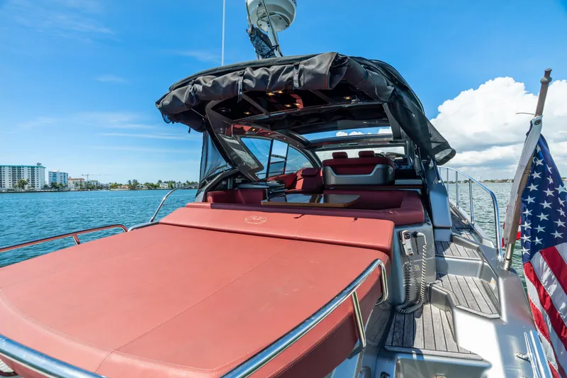 Damare Yacht Photos Pics 2022 Cranchi M 44 HT yacht with red seating, docked by the water, American flag visible.