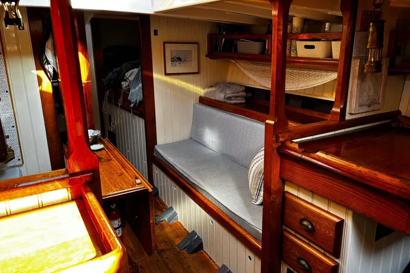 Hesper Yacht Photos Pics Cozy interior of 2004 Custom Luke Powell Pilot Cutter with wooden furnishings and seating.