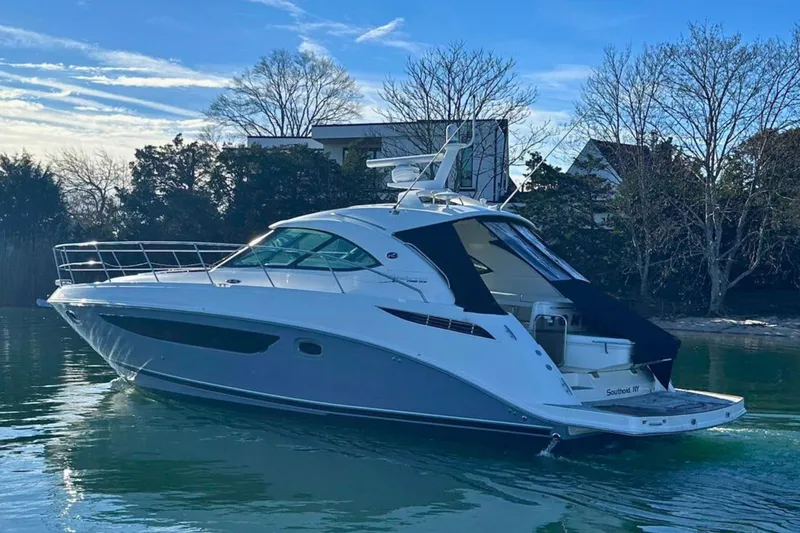  Yacht Photos Pics 2014 Sea Ray 410 Sundancer yacht on calm water, surrounded by trees and clear sky.