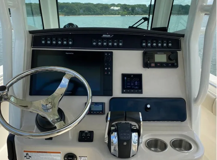 Patriot Yacht Photos Pics Control panel of a 2020 Boston Whaler 250 R boat with steering wheel and navigation equipment.