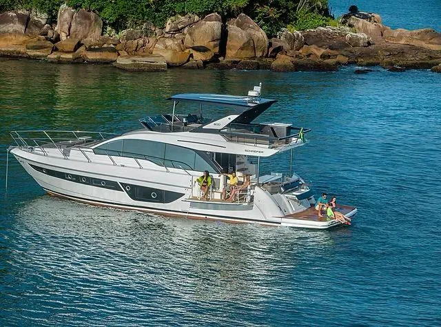  Yacht Photos Pics Luxurious 2026 Schaefer 600 yacht cruising near rocky shoreline with passengers enjoying the view.