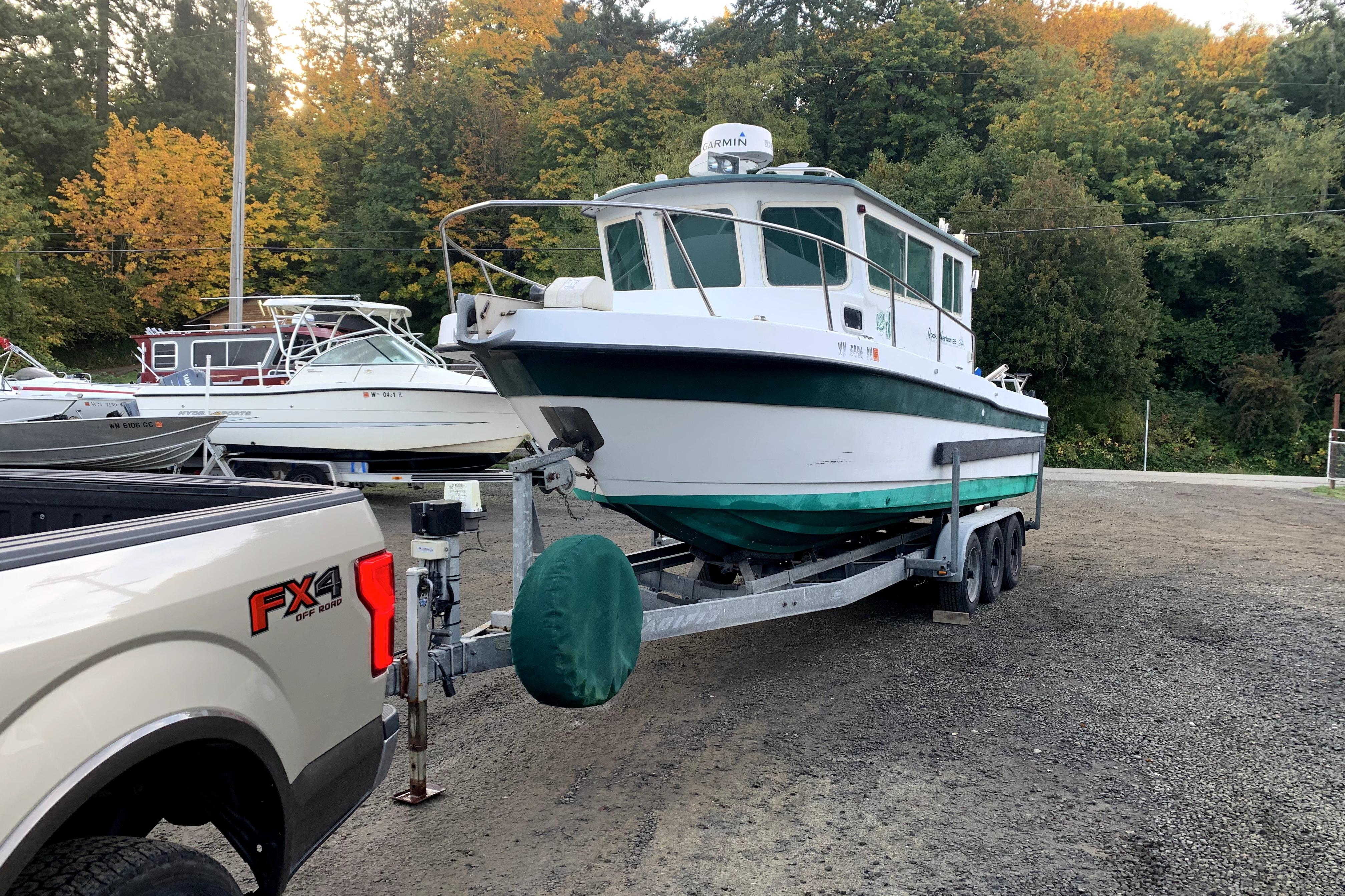 1998 Davis Rock Harbor 25 boat on trailer, surrounded by autumn trees.
