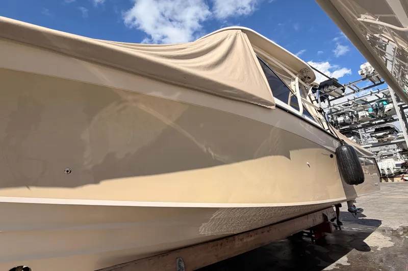  Yacht Photos Pics 2013 Grady-White Freedom 335 boat with beige cover, docked under a clear blue sky.