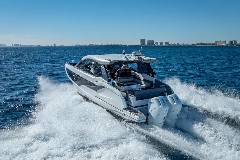  Yacht Photos Pics 2023 Galeon 375 GTO yacht cruising on open water, city skyline in background.
